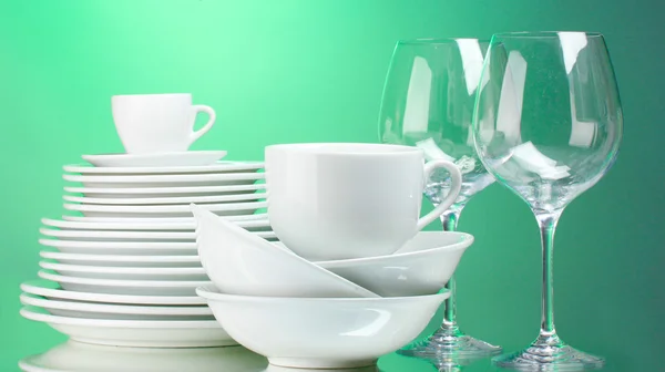 Platos, vasos y vasos limpios sobre fondo verde —  Fotos de Stock