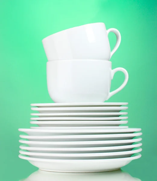 Saubere Teller und Tassen auf grünem Hintergrund — Stockfoto