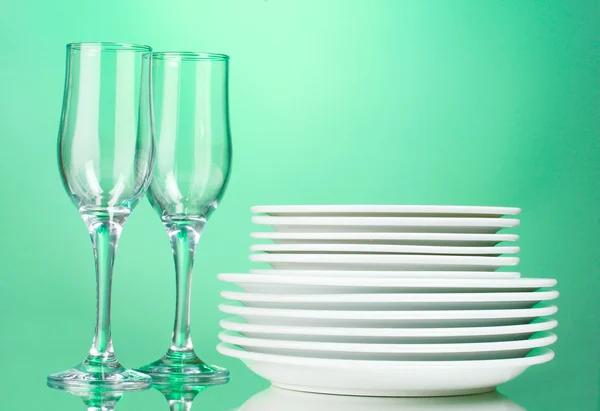 Czyste talerze i szklanki na zielonym tle — Zdjęcie stockowe