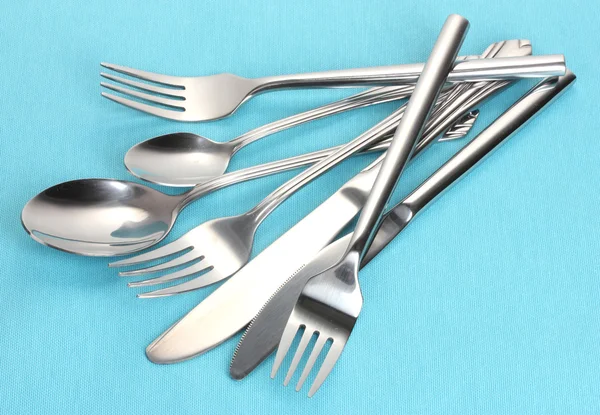 Tenedores, cucharas y cuchillos sobre un mantel azul — Foto de Stock