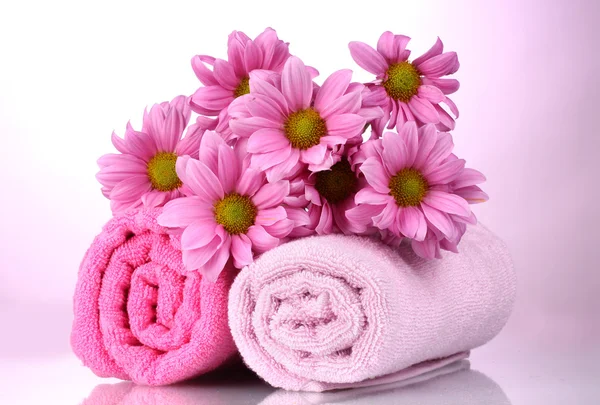 Полотенца и красивые цветы на розовом фоне — стоковое фото