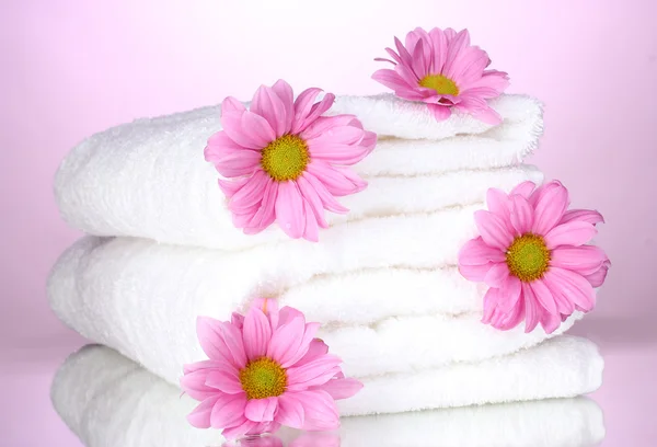 Ręczniki i piękne kwiaty na różowym tle — Zdjęcie stockowe