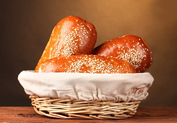 Gebackenes Brot im Korb auf Holztisch auf braunem Hintergrund — Stockfoto