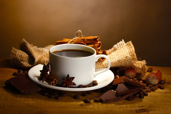コーヒー カップと豆、シナモンスティック、ナットおよびチョコレート木製テーブル o — ストック写真