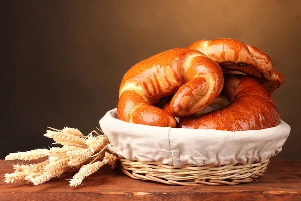 Gebackenes Brot im Korb auf Holztisch auf braunem Hintergrund — Stockfoto