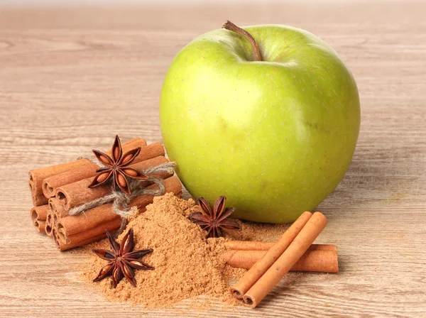 Tyčinky skořice, zelené jablko a anýzu na dřevěný stůl — Stock fotografie