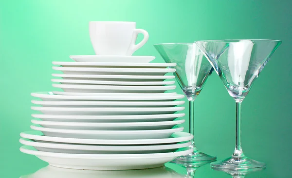 清洁盘子、 杯子和绿色背景上的眼镜 — 图库照片