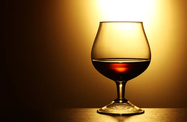 Glas cognac på gul bakgrund — Stockfoto