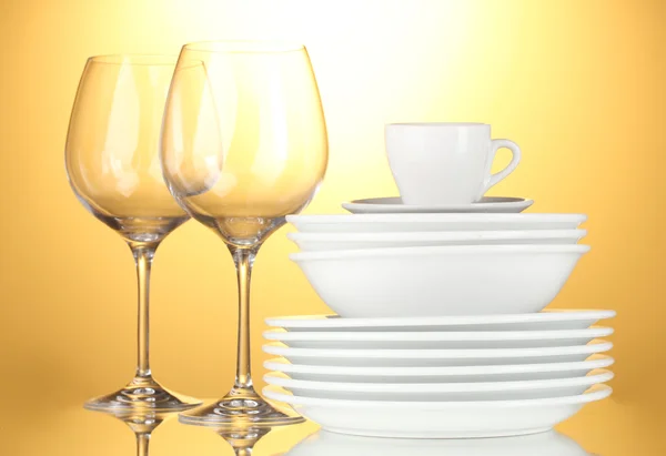 Tigelas vazias, pratos, copos e copos em fundo amarelo — Fotografia de Stock
