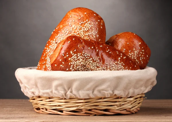 Pan horneado en cesta sobre mesa de madera sobre fondo gris —  Fotos de Stock