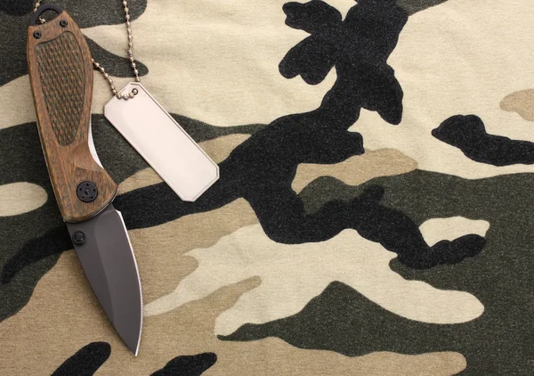 Армейские значки и нож на фоне камуфляжа — стоковое фото