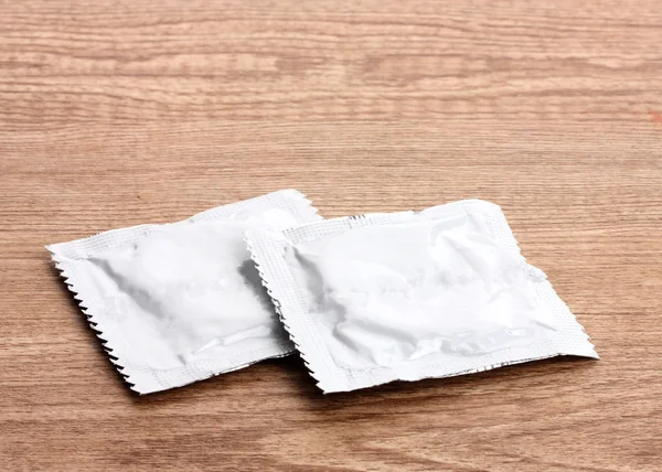 Один презерватив на деревянном фоне — стоковое фото