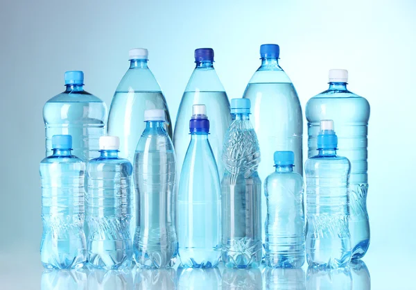 Groep plastic flessen water op blauwe achtergrond — Stockfoto