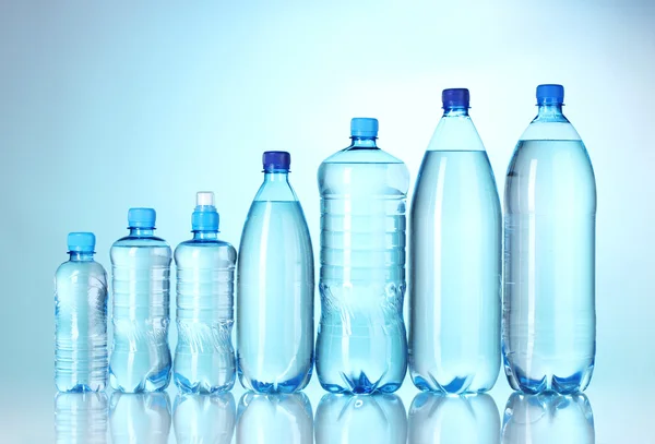Grupa plastikowe butelki wody na niebieskim tle — Zdjęcie stockowe