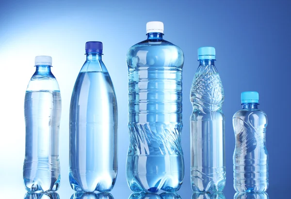 Skupina plastových lahví vody na modrém pozadí — Stock fotografie