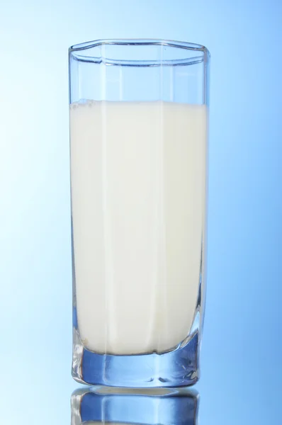 Tasty milk in glass on blue background — Stock Photo, Image