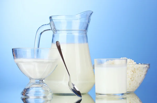 Latte, panna acida e fiocchi di latte su sfondo blu — Foto Stock