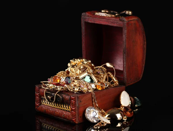 Houten kist vol van gouden sieraden op zwarte achtergrond — Stockfoto