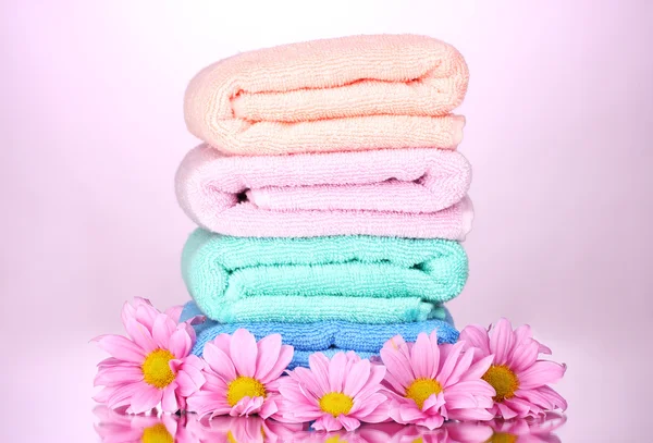 Pyyhkeet ja kauniit kukat vaaleanpunaisella taustalla — kuvapankkivalokuva