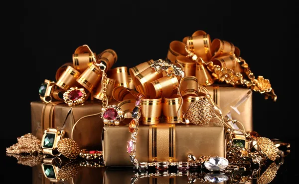 Various gold jewellery and gifts on black background — Stock Photo, Image