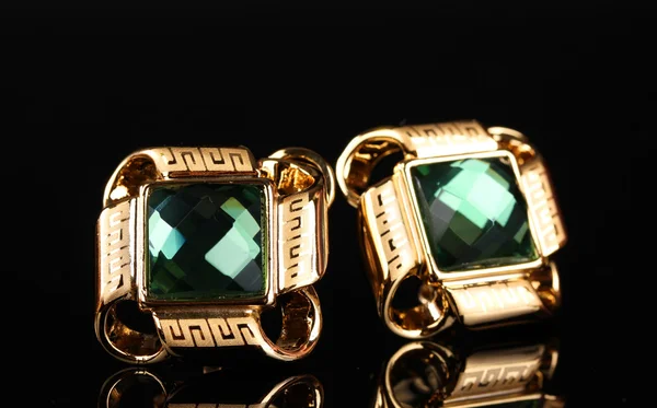 Belos brincos de ouro com esmeralda sobre fundo preto — Fotografia de Stock