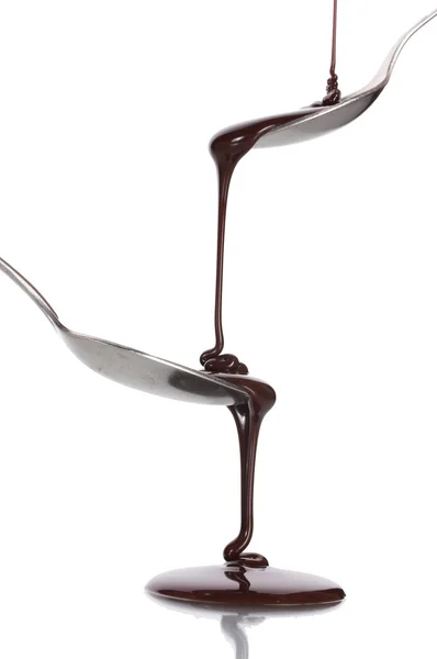巧克力浇入一把勺子和从它到另一个勺子隔离对惠特 — 图库照片
