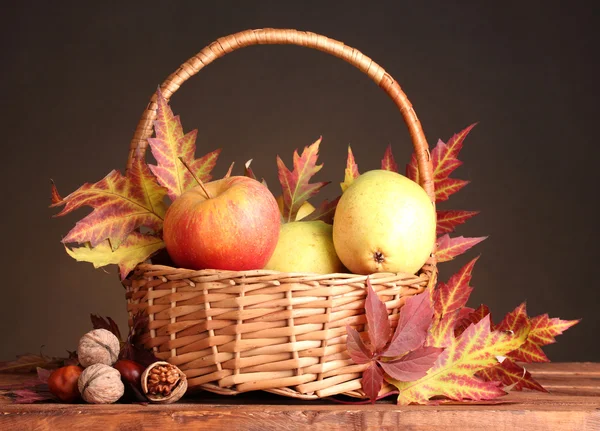 Beautiful autumn harvest in basket and leaves on brown background — Stock Photo, Image