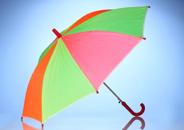Wielo--kolorowy parasol na niebieskim tle — Zdjęcie stockowe