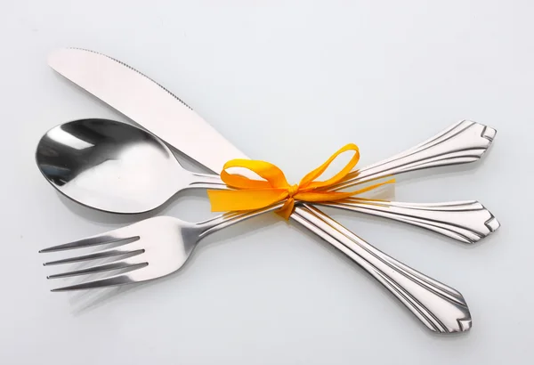 Silver fork and spoon, knife tied with a yellow ribbon isolated on white — Stock Photo, Image