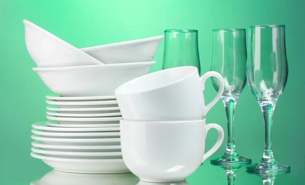 Saubere Teller, Tassen und Gläser auf grünem Hintergrund — Stockfoto