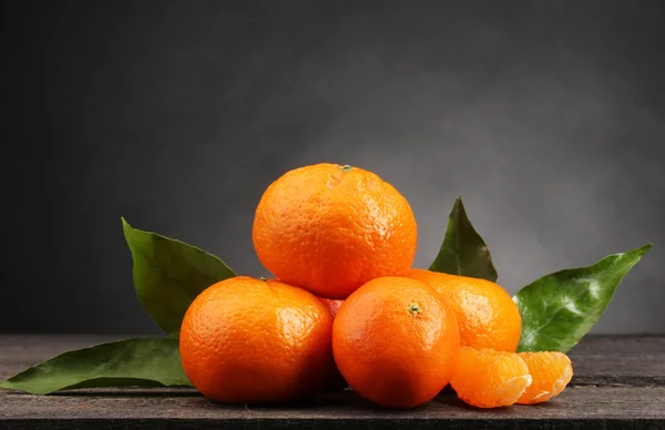 Mandarinen mit Blättern auf Holztisch auf grauem Hintergrund — Stockfoto