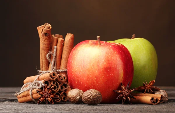 Bastoncini di cannella, mele noce moscata e anice su tavolo di legno su sfondo marrone — Foto Stock