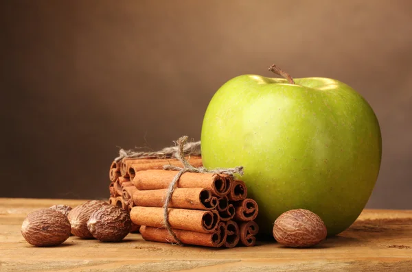 Fahéj rúd, a zöld alma és a szerecsendió a fából készült asztal barna háttér — Stock Fotó