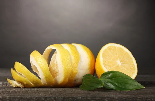 Limoni maturi con foglie su tavola di legno su fondo grigio — Foto Stock
