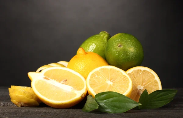 Limones maduros y limas con hojas sobre mesa de madera sobre fondo gris —  Fotos de Stock