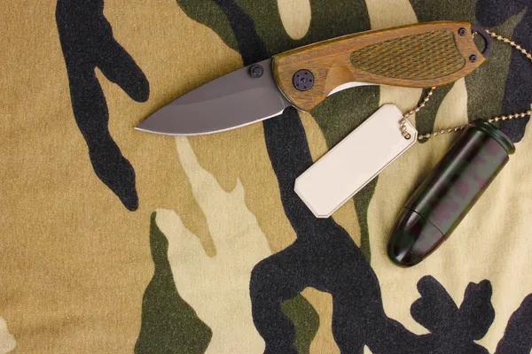 Армійські значки і ніж на камуфляжному фоні — стокове фото