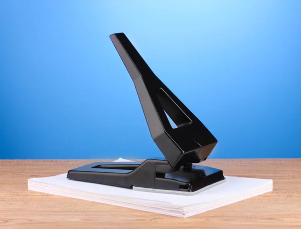 Schwarzes Büroloch mit Papier auf blauem Hintergrund — Stockfoto