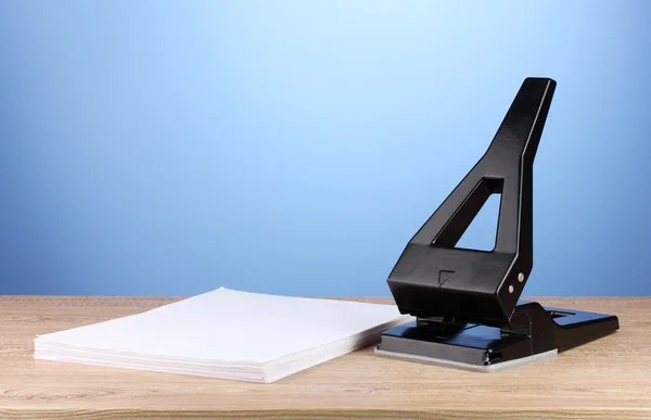 Poinçon de bureau noir avec papier sur fond bleu — Photo