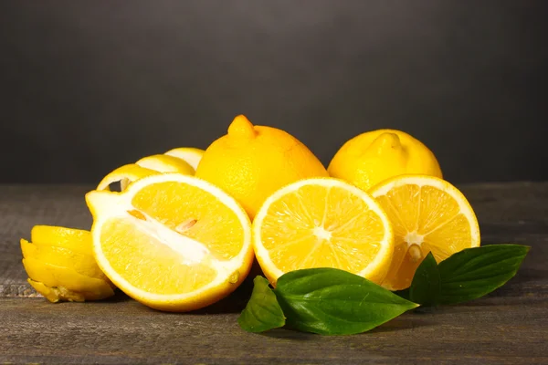 Mogna citroner med blad på träbord på grå bakgrund — Stockfoto