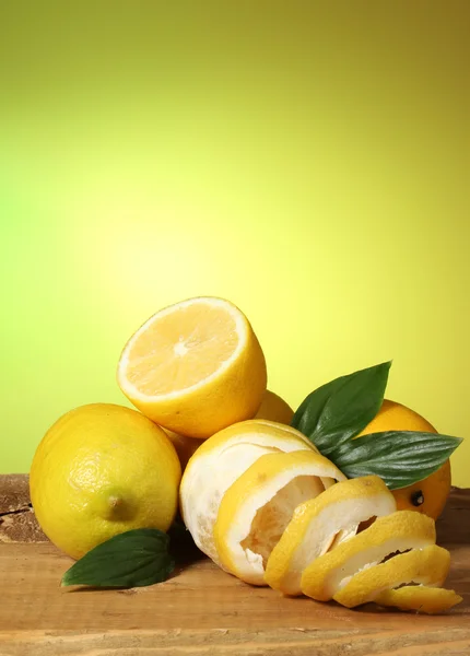 Mogna citroner med blad på träbord på grön bakgrund — Stockfoto
