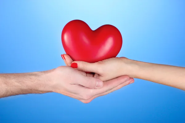Mann und Frau mit rotem Herz in der Hand auf blauem Hintergrund — Stockfoto