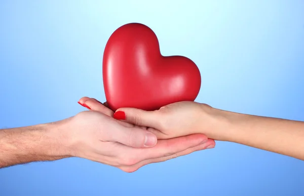 Férfi és nő piros szív tartja kezében a kék háttér — Stock Fotó