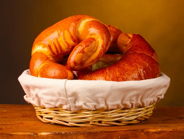 Pečený chleba v koši na dřevěný stůl na hnědé pozadí — Stock fotografie