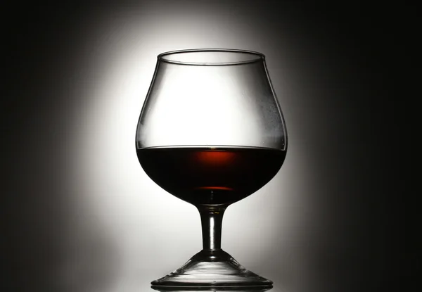 Glass of cognac on grey background — Stock Photo, Image