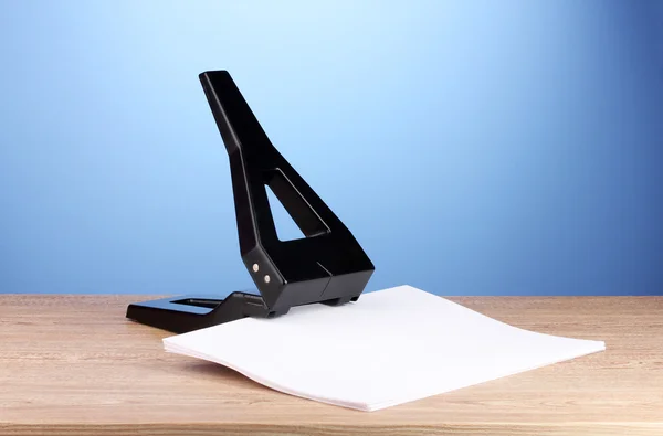 Poinçon de bureau noir avec papier sur fond bleu — Photo