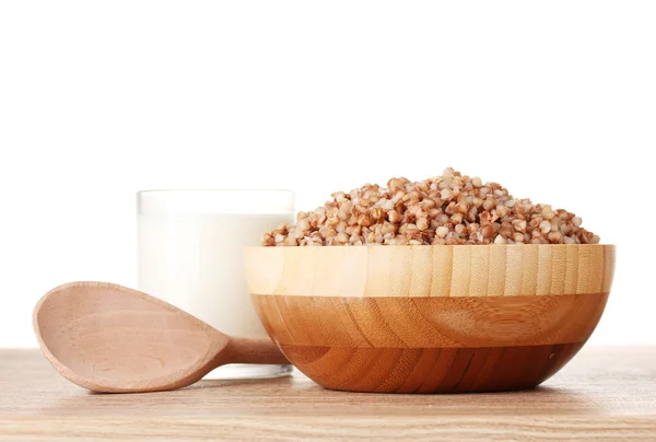 Boiled buckwheat in a wooden bowl with a glass of milk on wooden table isol — Stock Photo, Image