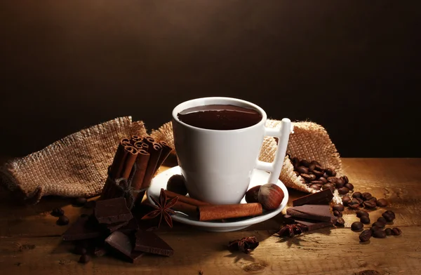 Kopje warme chocolademelk, kaneelstokjes, noten en chocolade op houten tafel o — Stockfoto
