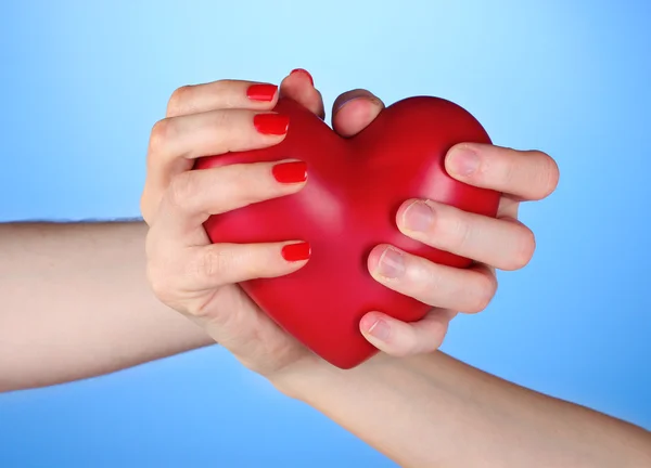 Man och kvinna med rött hjärta i händerna på blå bakgrund — Stockfoto