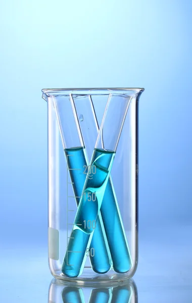 Tubos de laboratório com líquido azul em copo de medição com reflexão sobre bl — Fotografia de Stock