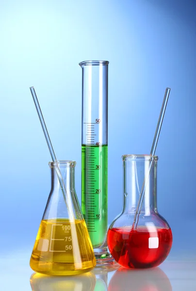 Three flasks with color liquid with reflection on blue background — Stock Photo, Image